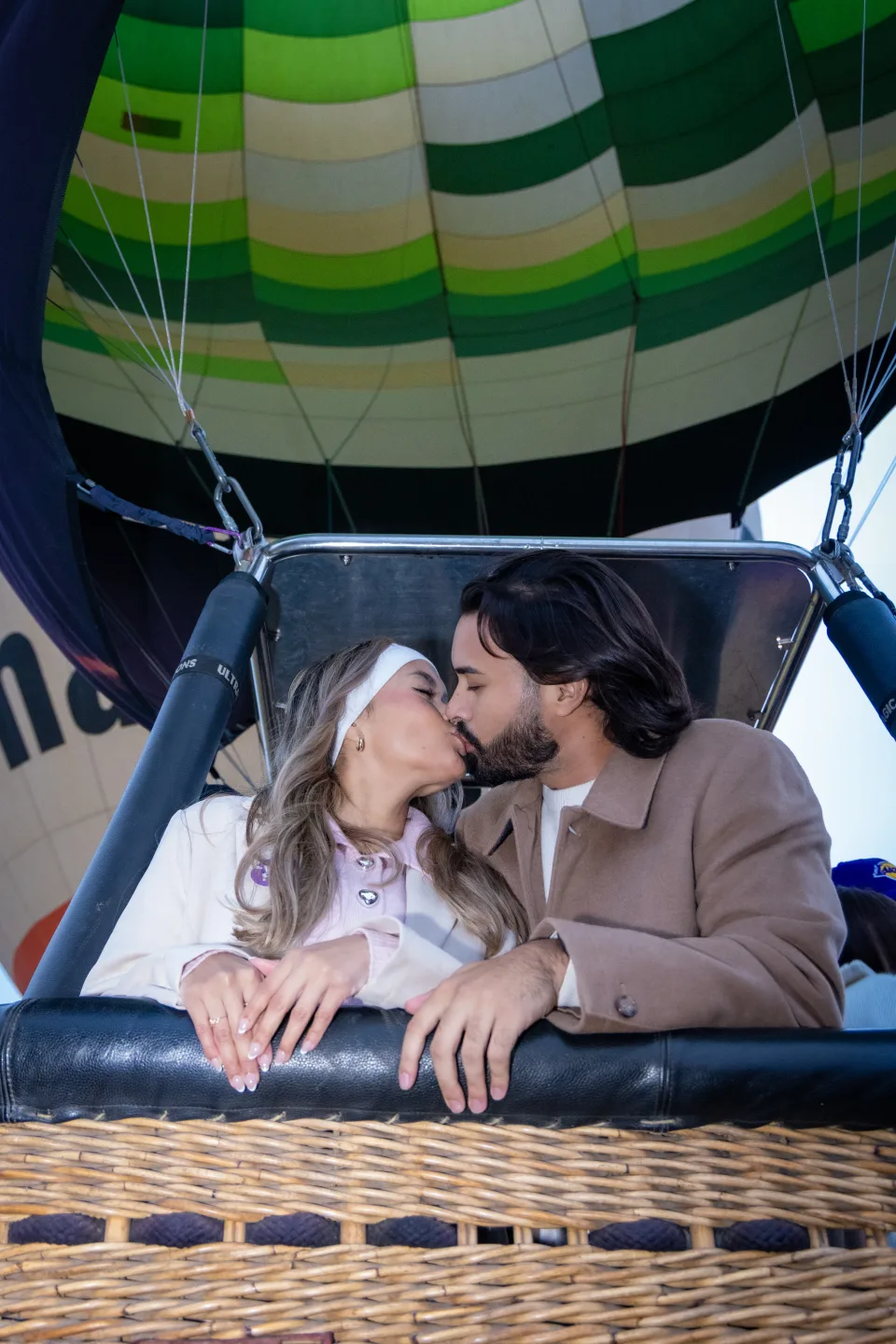 Couple kissing inside a hot air balloon basket at sunrise over Teotihuacan