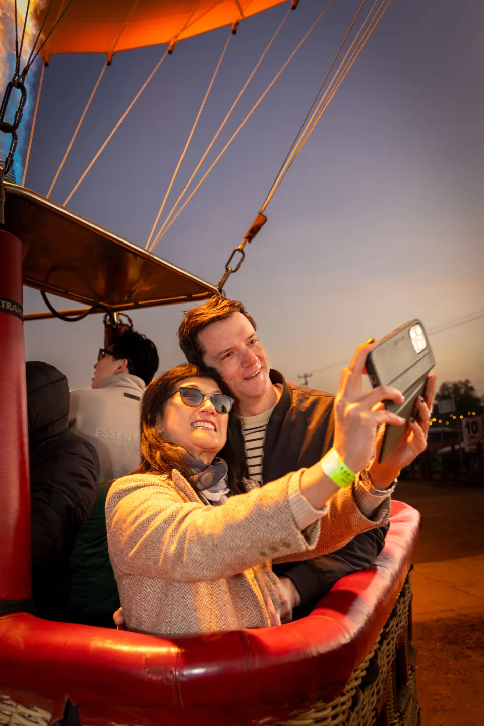 Mother and son taking a selfie inside a balloon basket in warm sunrise light