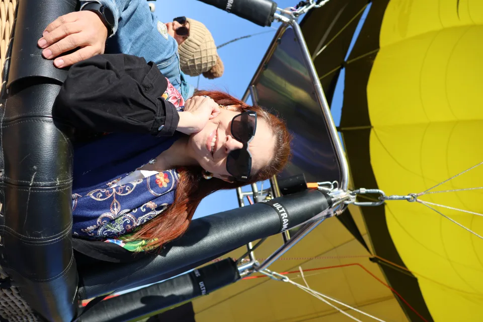Relaxed woman in a hot air balloon basket in flight under a yellow canopy