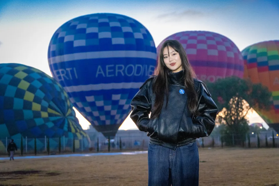 Woman posing in front of a large blue hot air balloon at dawn in Teotihuacan