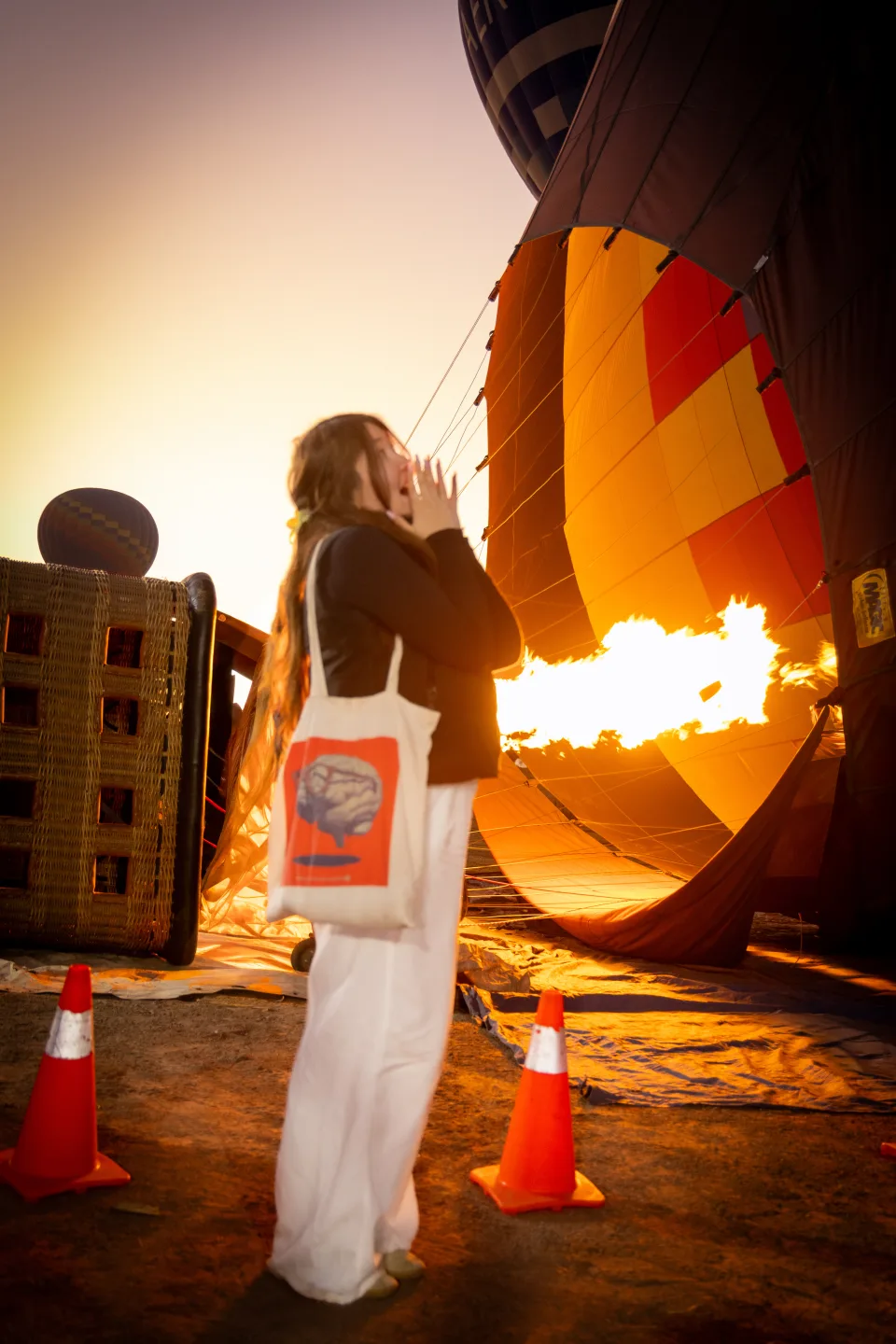 Woman backlit by the burner flame in golden sunrise light over Teotihuacan