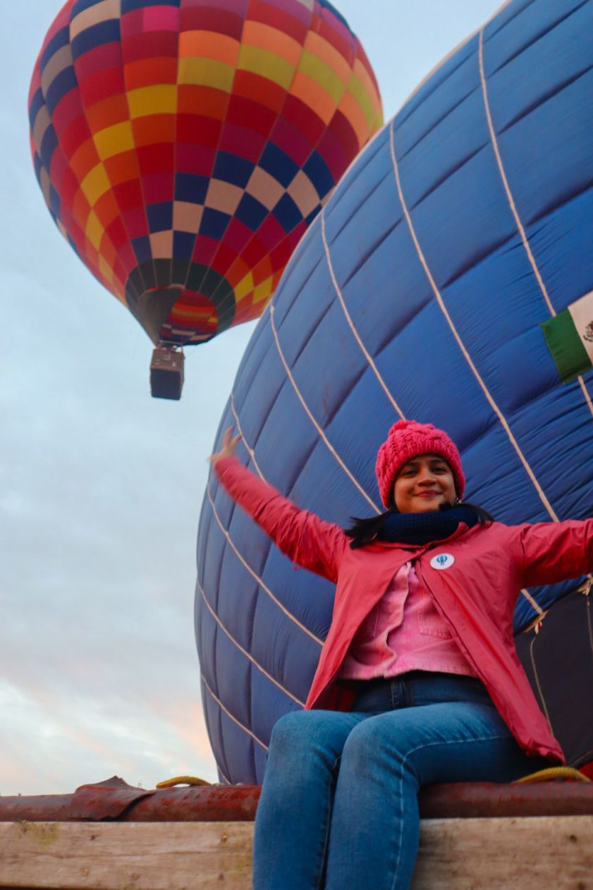 Hot air balloon flight plus breakfast in a cave: woman with open arms next to the balloon in Teotihuacan