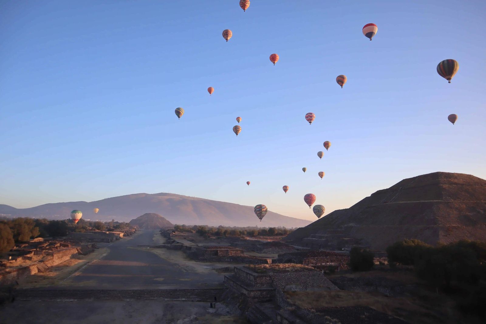 Dozens of hot air balloons over the Avenue of the Dead and the Pyramid of the Sun at sunrise